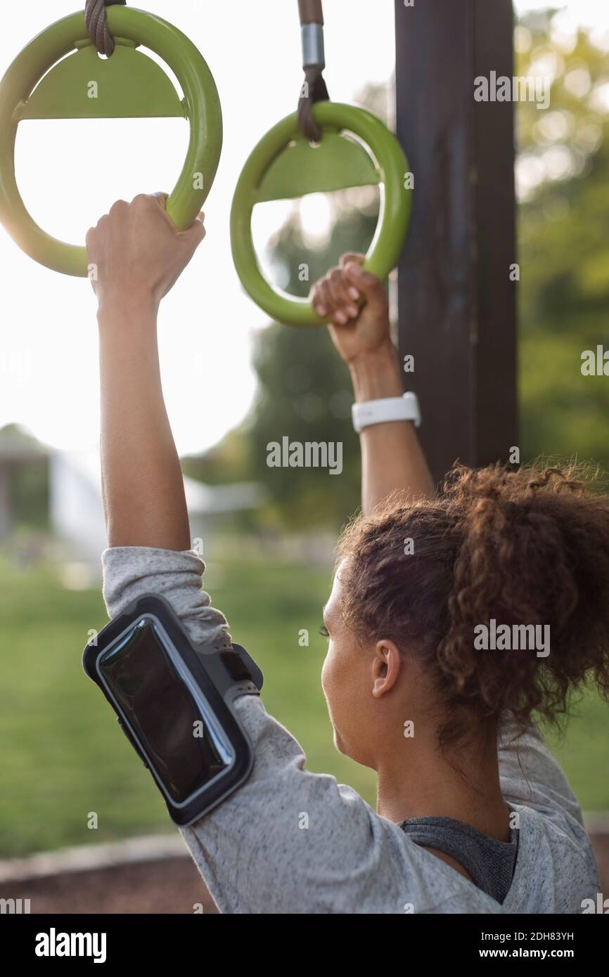 Femme accrochée à des anneaux de gymnastique au parc Banque D'Images