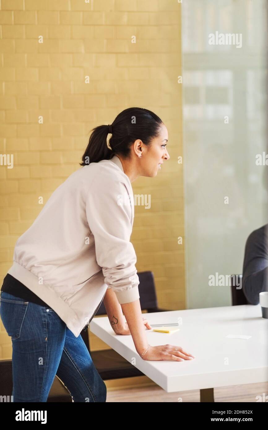 Vue latérale d'une jeune femme d'affaires qui se penche sur une table de conférence Banque D'Images