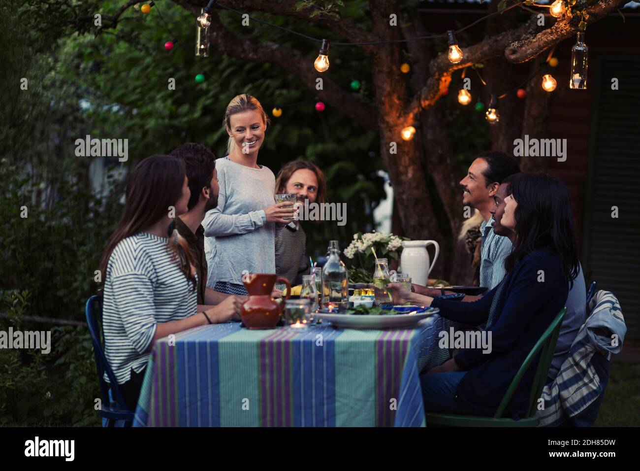 Bonne femme qui parle à des amis assis à la table du dîner cour Banque D'Images