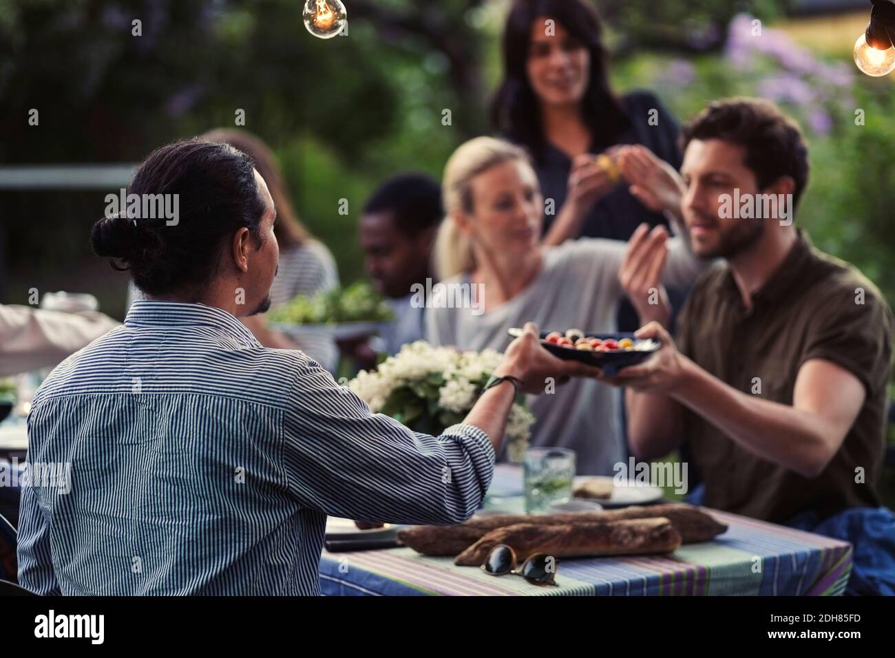 Les hommes passent la nourriture à la table à manger pendant le dîner à cour Banque D'Images