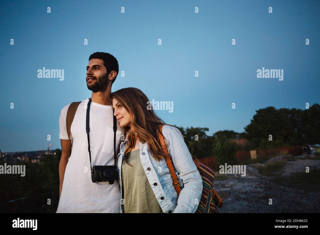 Un couple de touristes attentionnés qui regarde loin tout en se tenant contre le bleu clair ciel Banque D'Images
