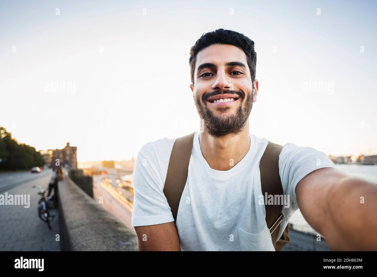 Portrait d'un touriste heureux assis sur le mur de soutènement de pont Banque D'Images