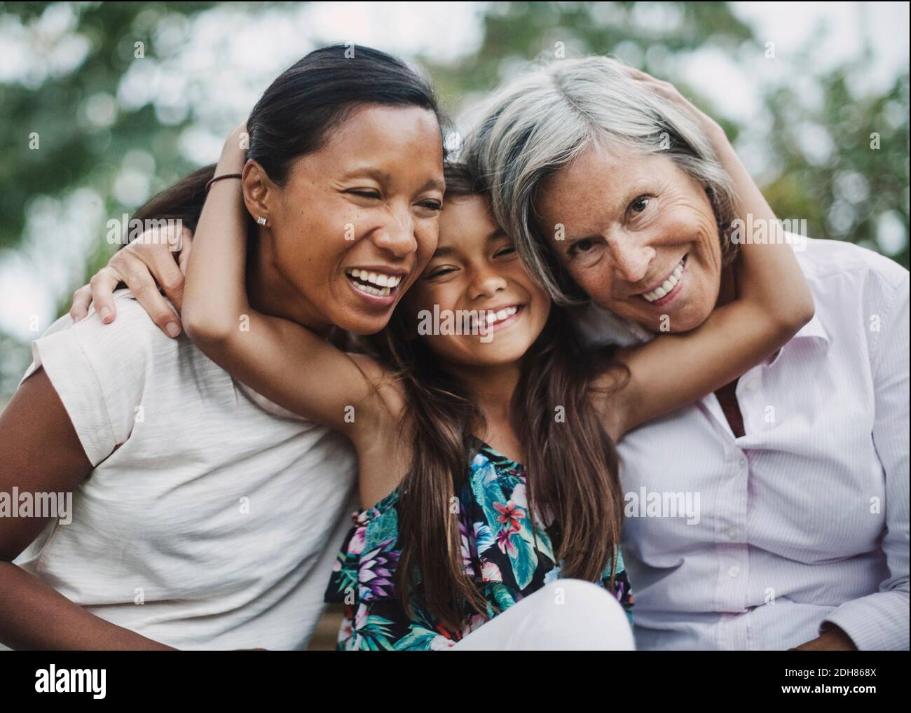 Portrait d'une fille heureuse embrassant mère et grand-mère à la cour Banque D'Images