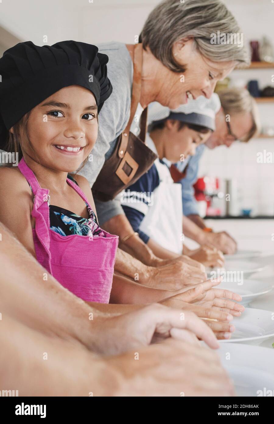 Portrait de la bonne fille préparant des aliments avec la famille dans la cuisine Banque D'Images