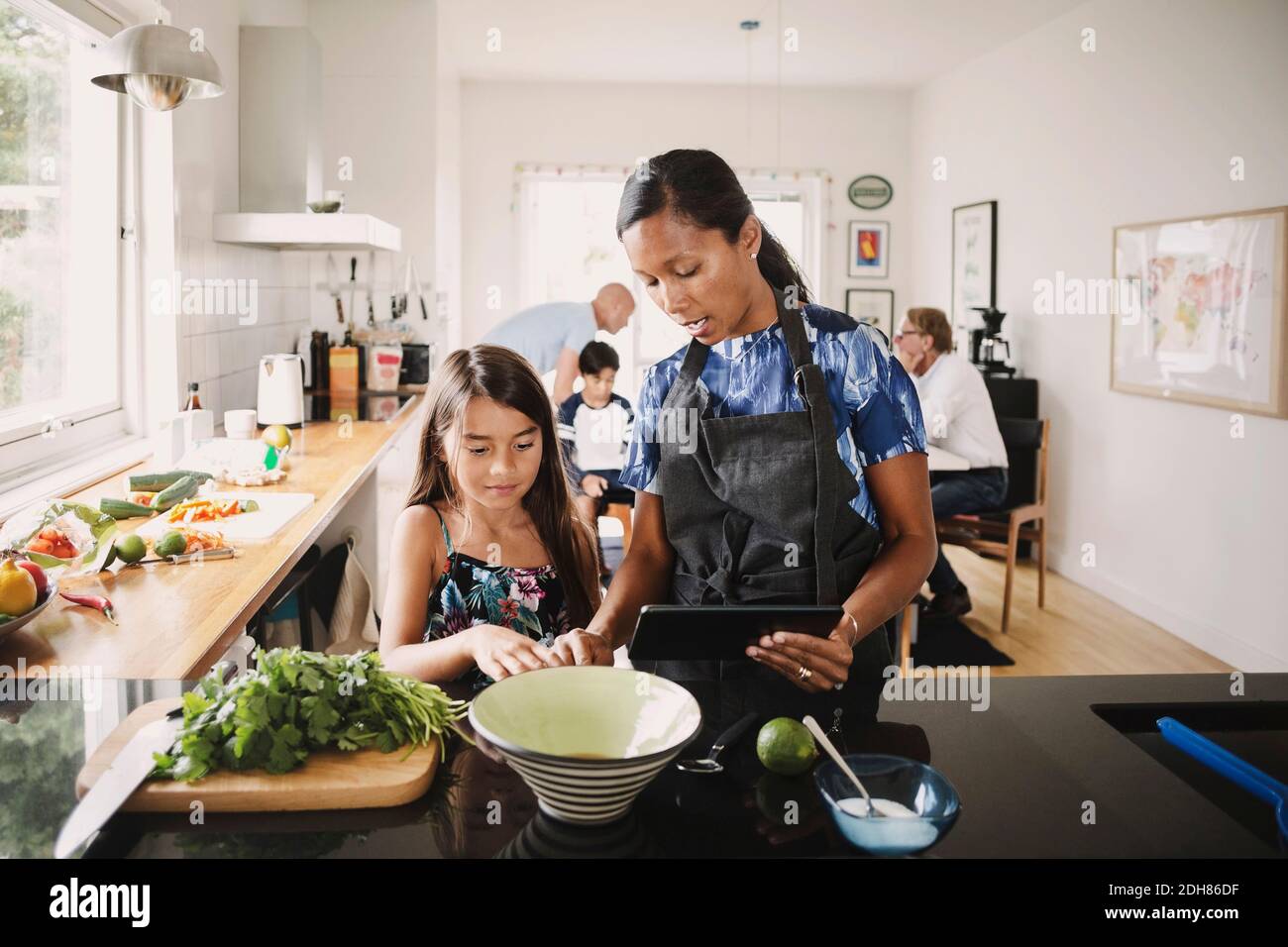 Mère et fille utilisant une tablette numérique pendant la préparation des aliments cuisine Banque D'Images