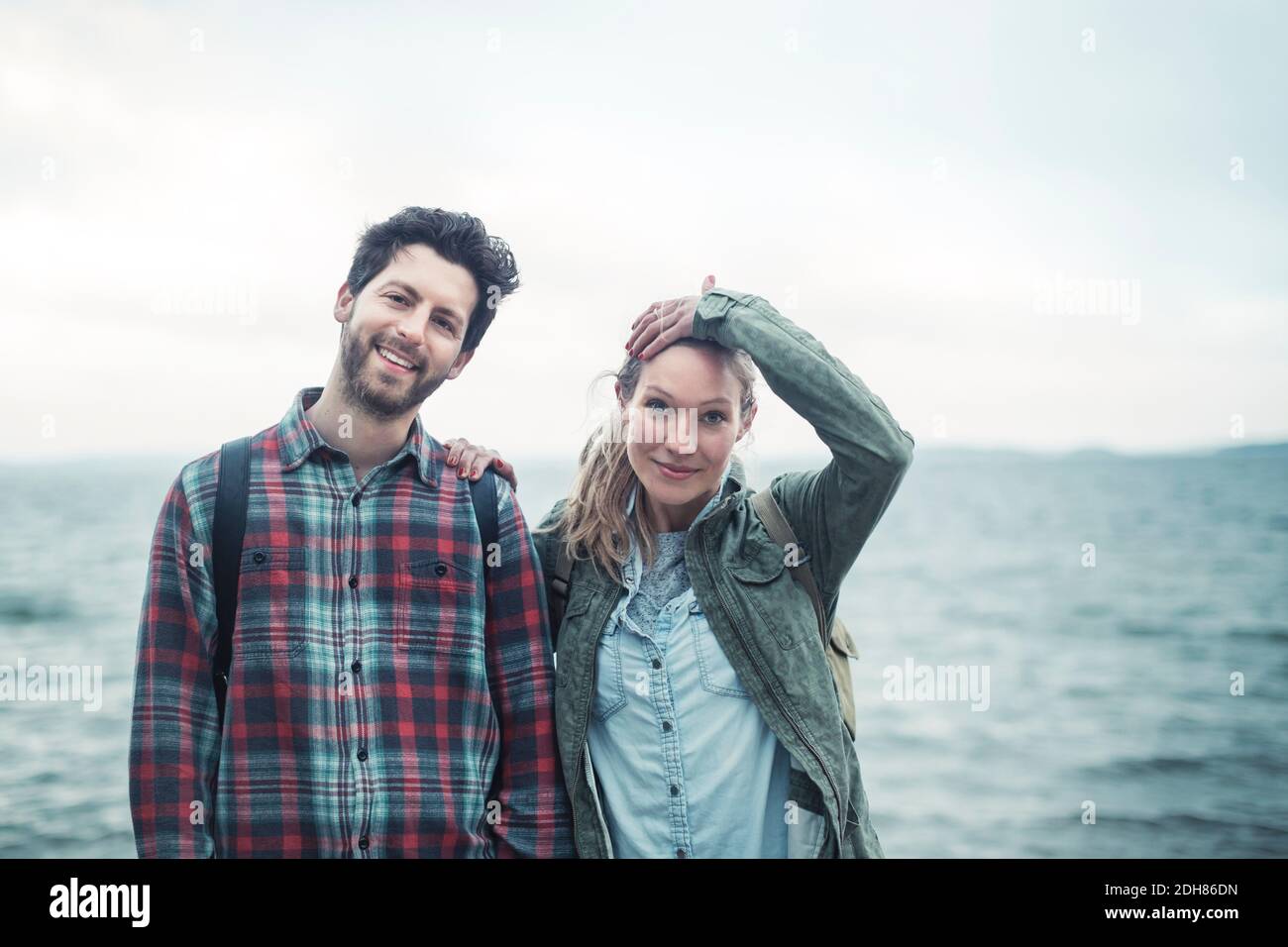 Portrait d'un couple d'émerveillement confiant debout contre la mer Banque D'Images