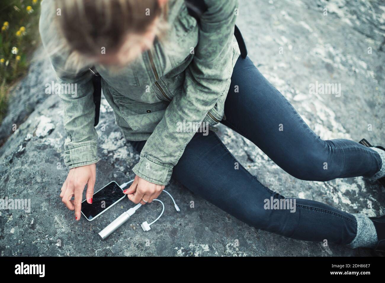 Vue en grand angle de la femme qui connecte le chargeur portable à SMART téléphone sur rock Banque D'Images