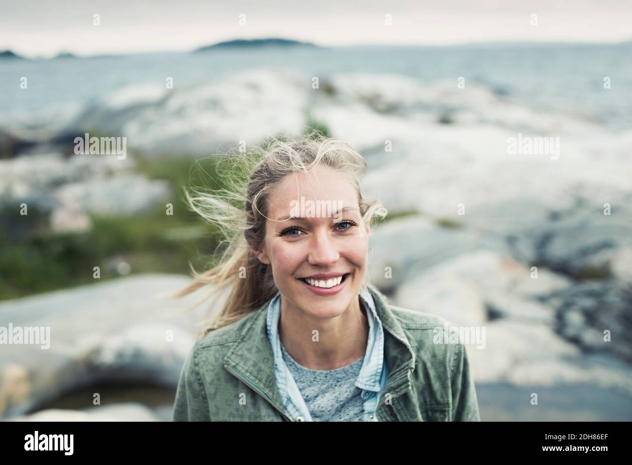 Portrait de la jeune femme heureuse sur le rocher par la mer Banque D'Images