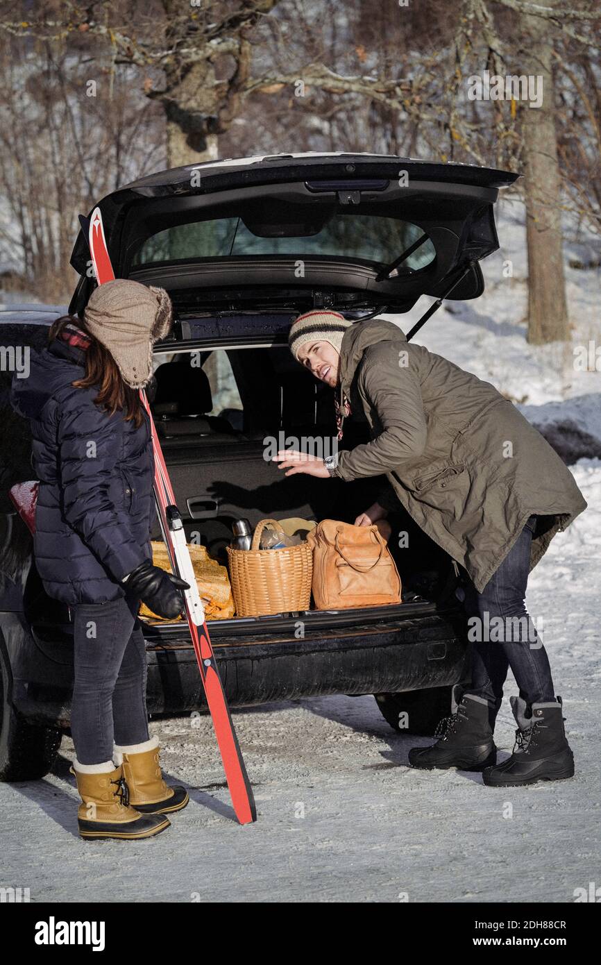 Jeune homme communiquant avec une femme lors du chargement du coffre de la voiture Banque D'Images