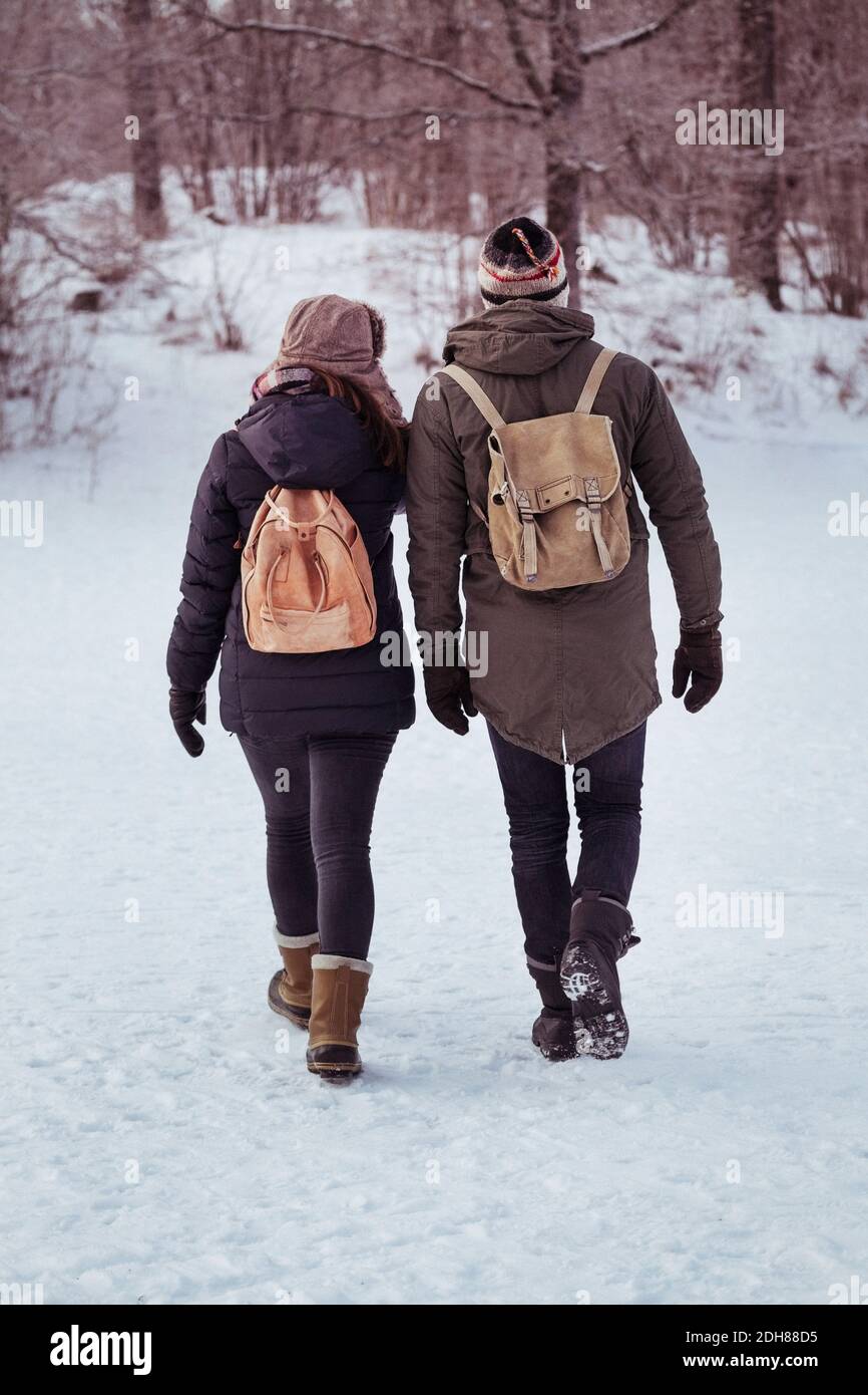 Vue arrière en longueur du couple marchant sur de la neige champ Banque D'Images