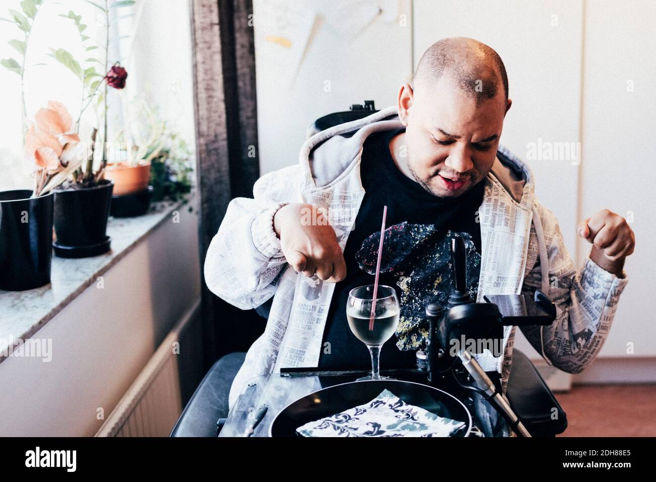 Homme handicapé avec un verre en fauteuil roulant motorisé au studio Banque D'Images