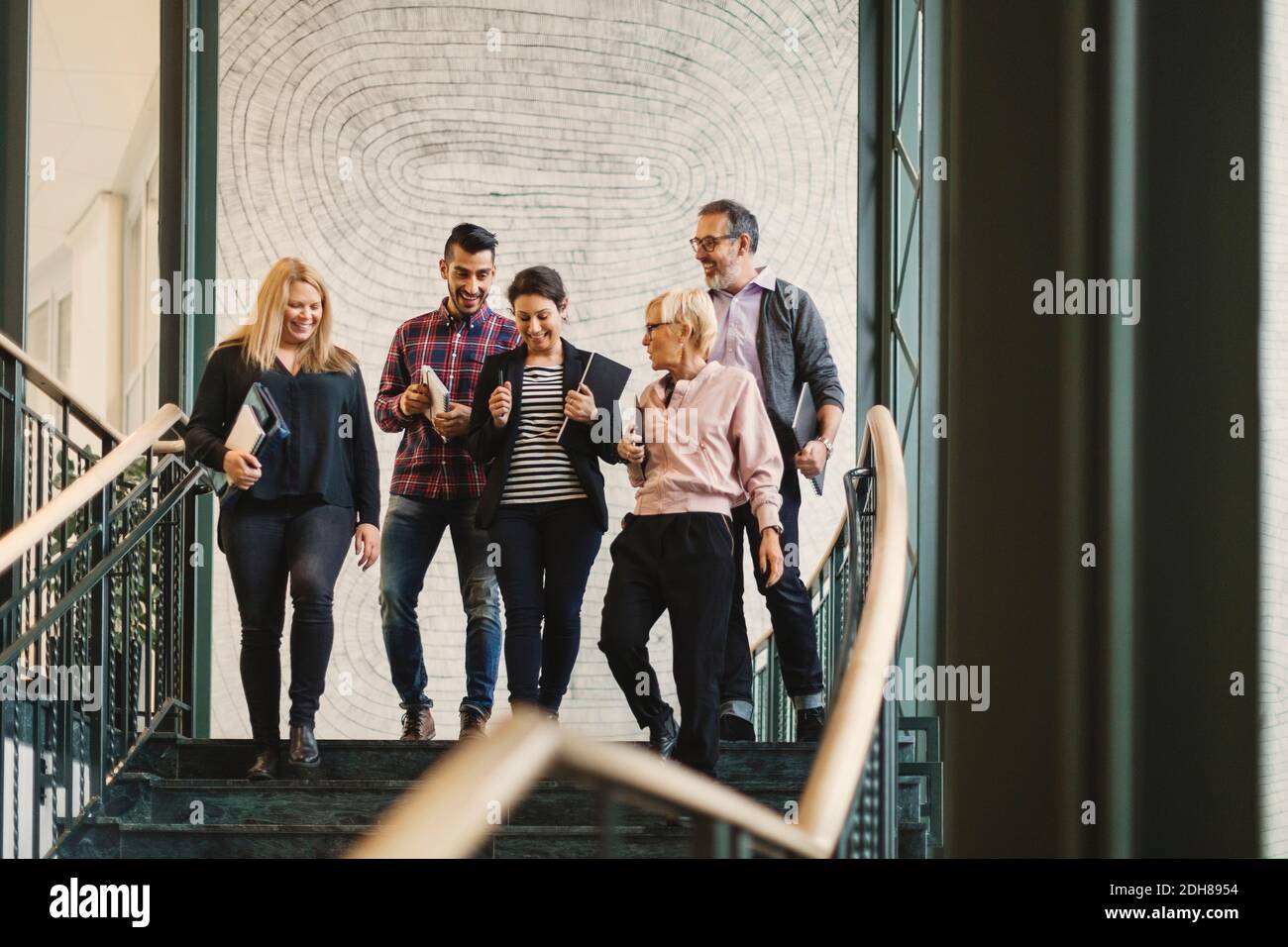 Équipe de professionnels créatifs qui se déplacent au rez-de-chaussée au bureau Banque D'Images