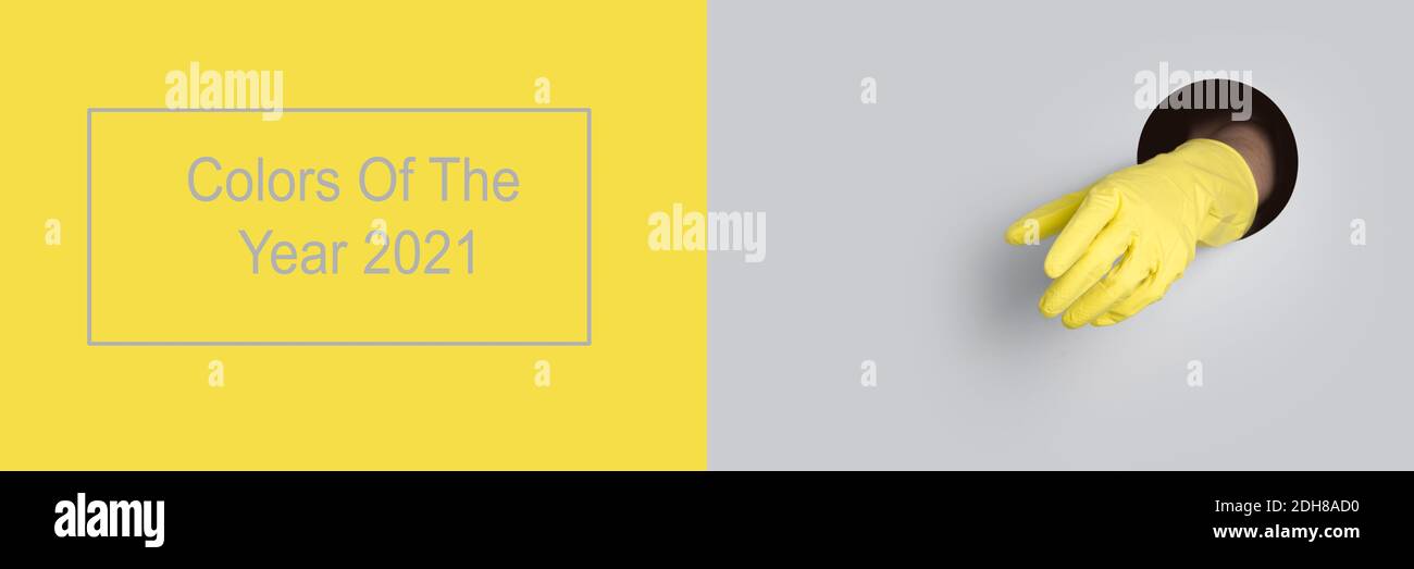 Gant jaune sur fond de trou gris. Bannière tendance avec la couleur Ultimate Grey et illuminant de l'année 2021. Banque D'Images