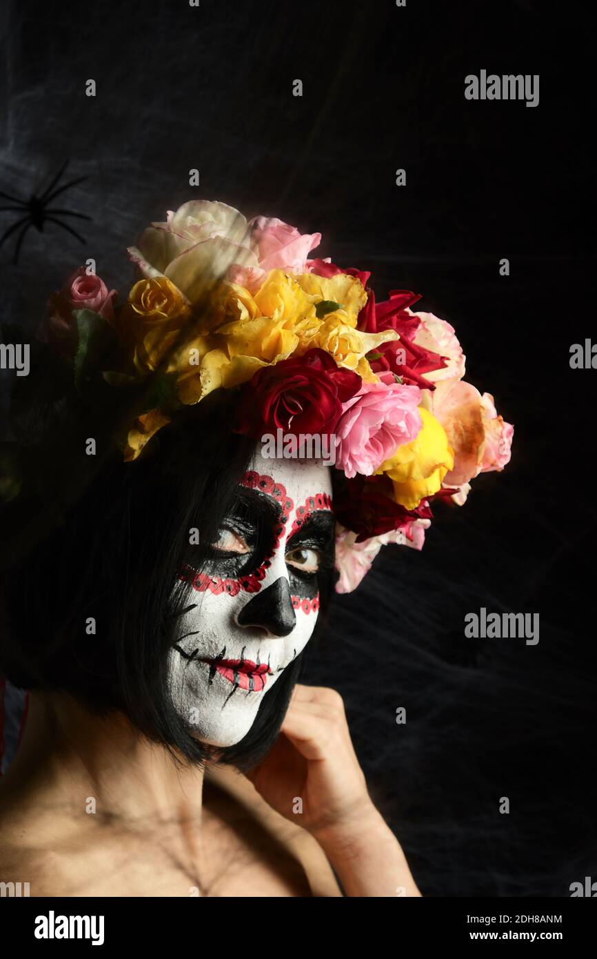 La femme d'apparence caucasienne est habillée dans une couronne de roses multicolores. Crâne de sucre Halloween M Banque D'Images