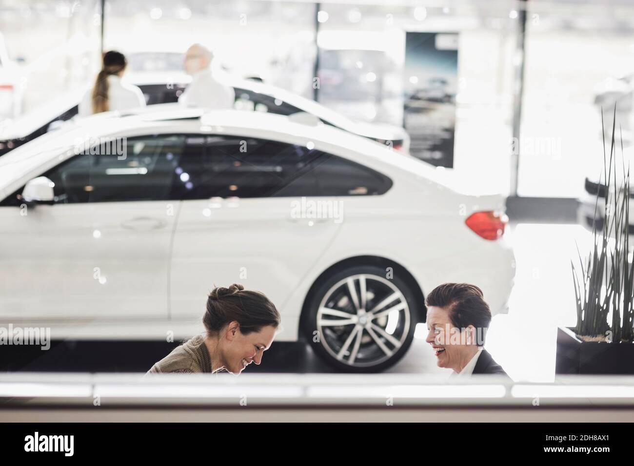 Femmes souriantes discutant en voiture dans la salle d'exposition Banque D'Images