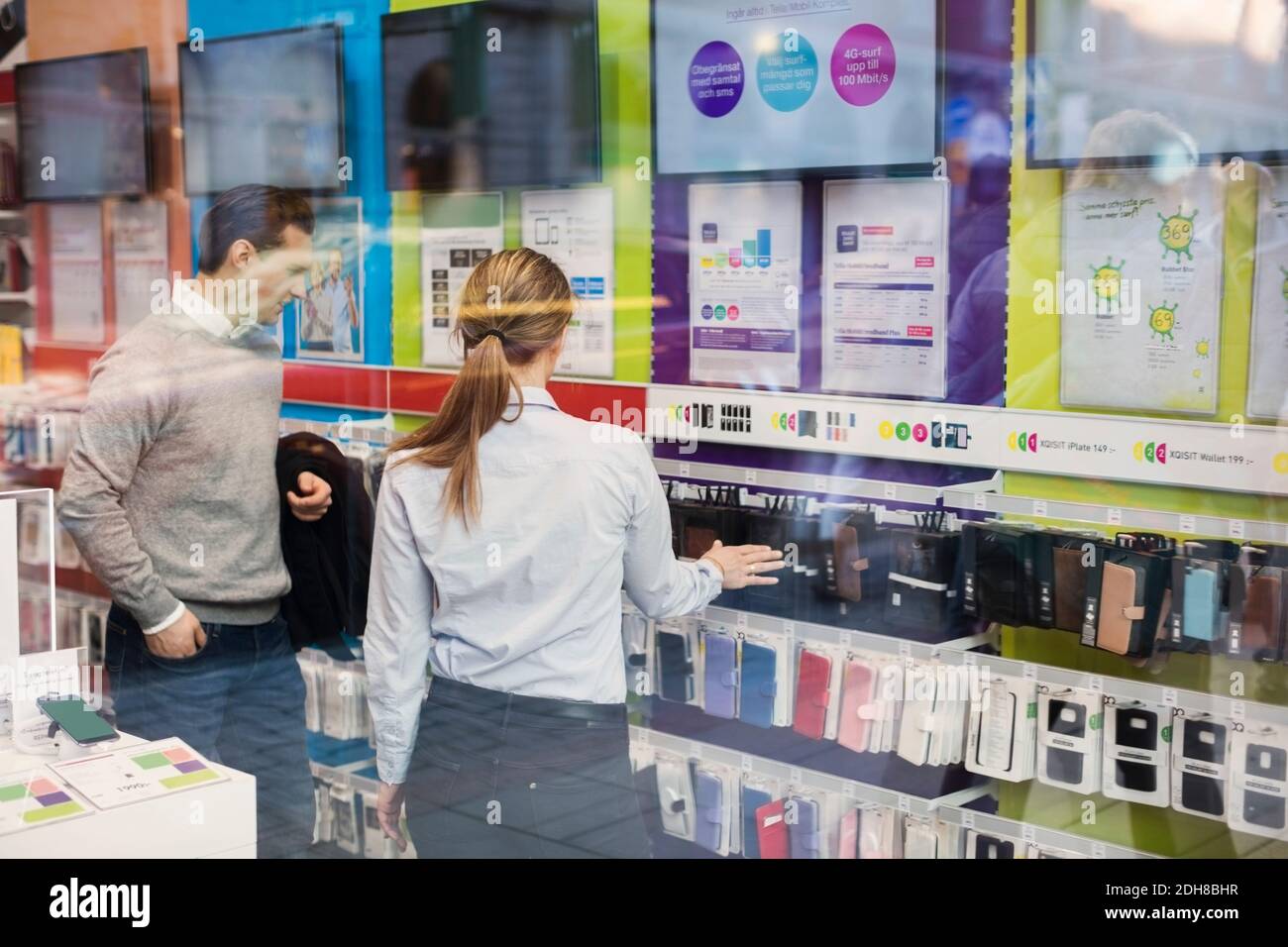 Vendeur aidant le client à acheter une housse de téléphone visible à travers le verre Banque D'Images