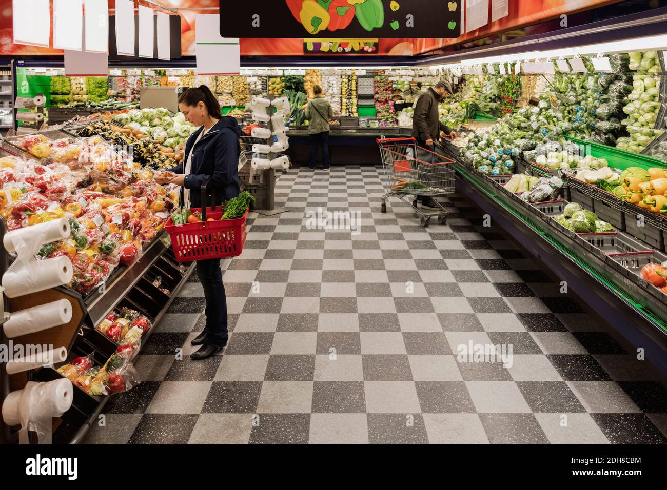 Les gens achetant des légumes en se tenant au supermarché Banque D'Images