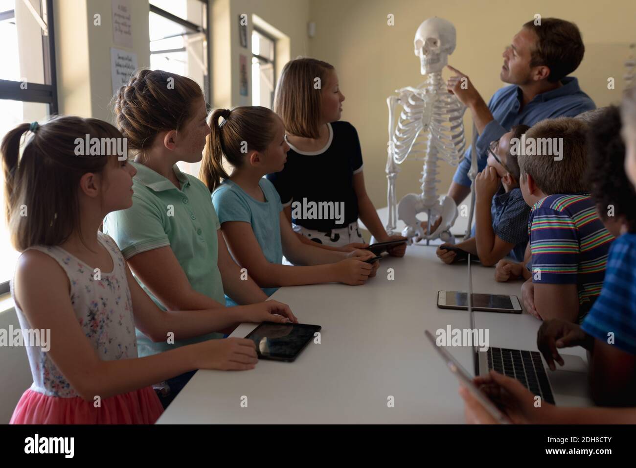 Professeur de sexe masculin utilisant un modèle de squelette humain à enseigner Banque D'Images