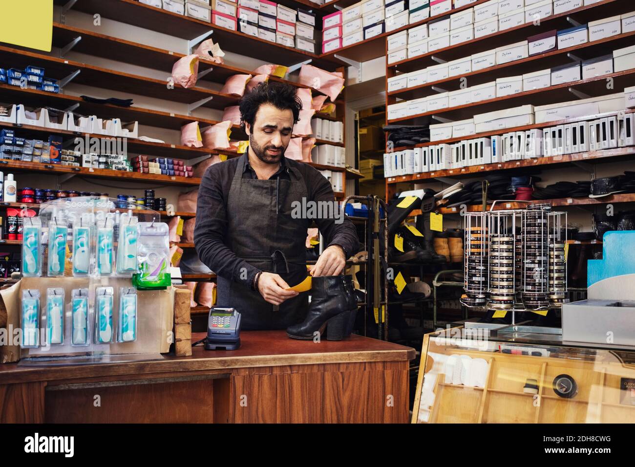 Le propriétaire lit l'étiquette de nom lorsqu'il se trouve au magasin de chaussures Banque D'Images