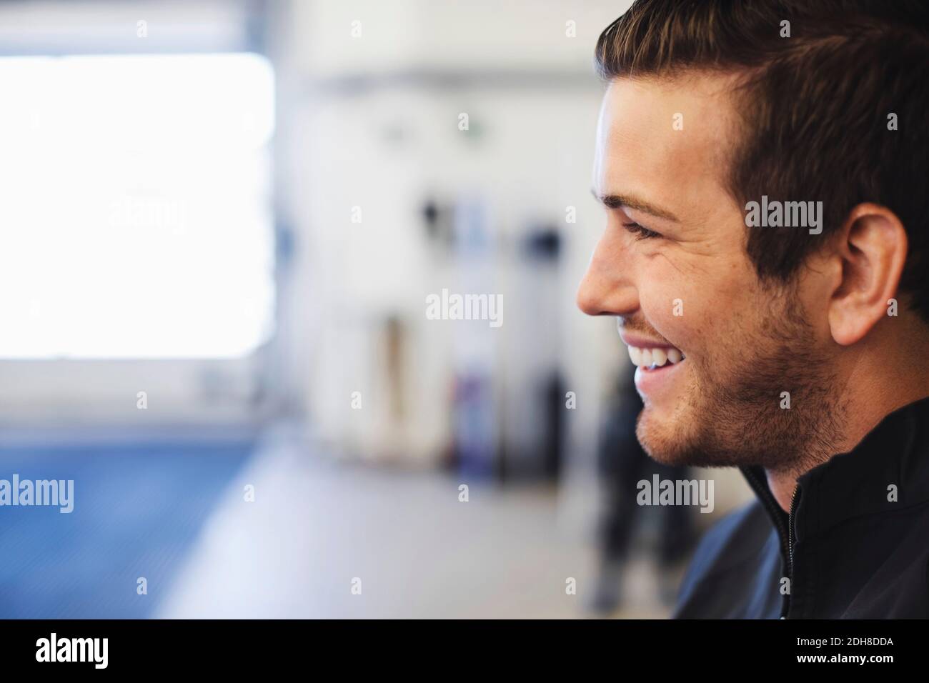 Vue du profil de Happy Mechanic dans l'atelier de réparation automobile Banque D'Images