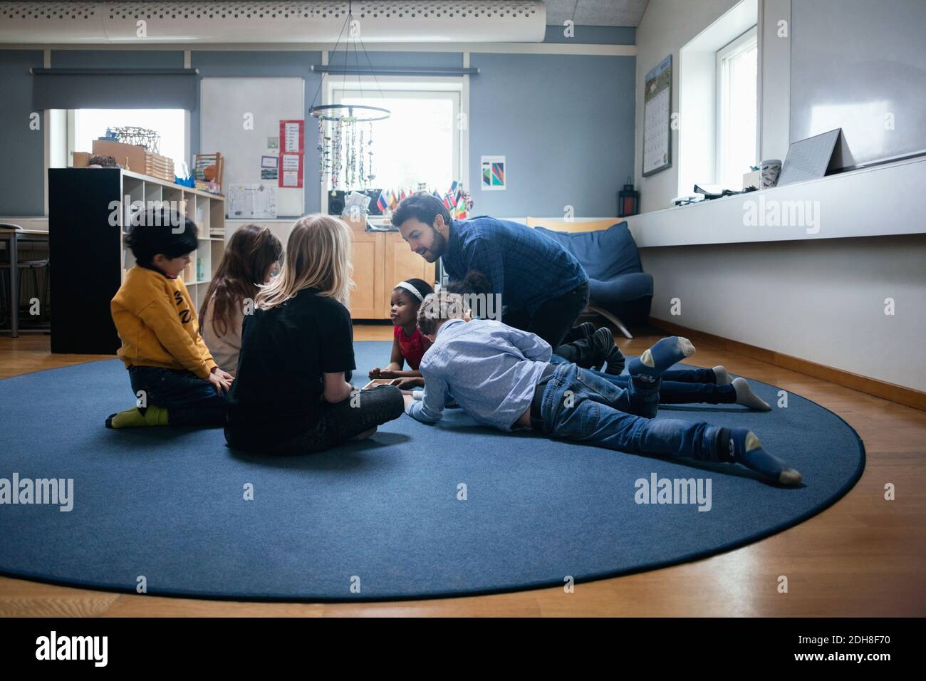 Professeur jouant avec les enfants sur le sol à l'école Banque D'Images