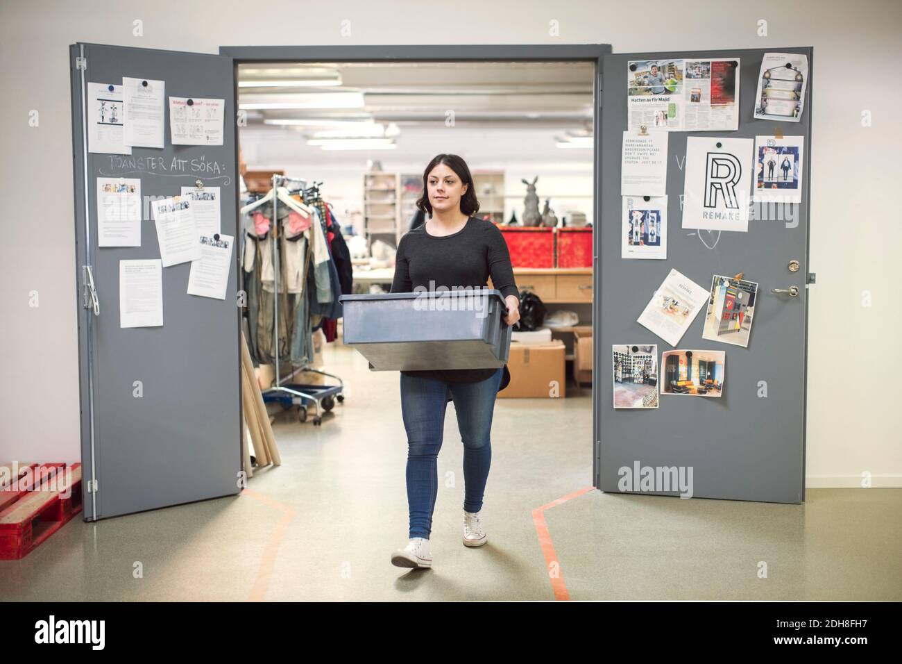 Femme transportant une caisse en sortant de l'entrée de l'atelier Banque D'Images