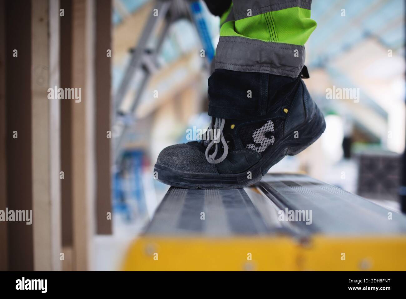 Section basse de l'homme portant des chaussures debout sur l'échelle Banque D'Images