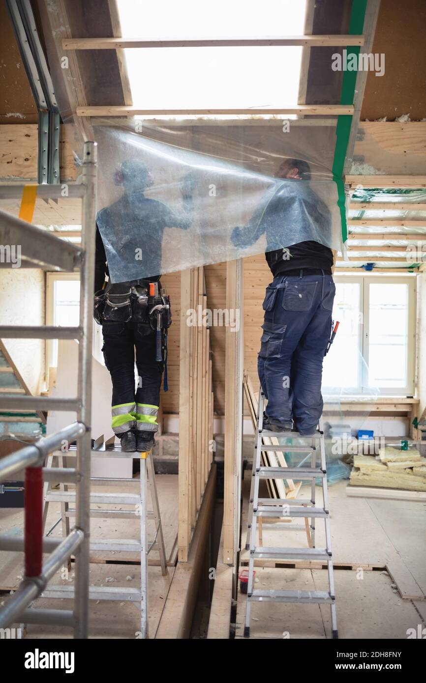 Vue à angle bas des travailleurs manuels travaillant sur une porte en bois sur le chantier Banque D'Images