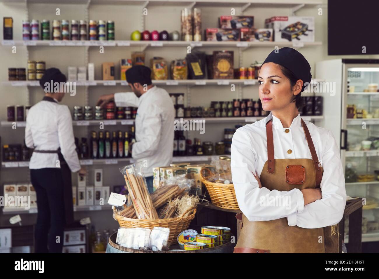 Un propriétaire attentionné croise les bras pendant que ses collègues travaillent à l'épicerie stocker Banque D'Images
