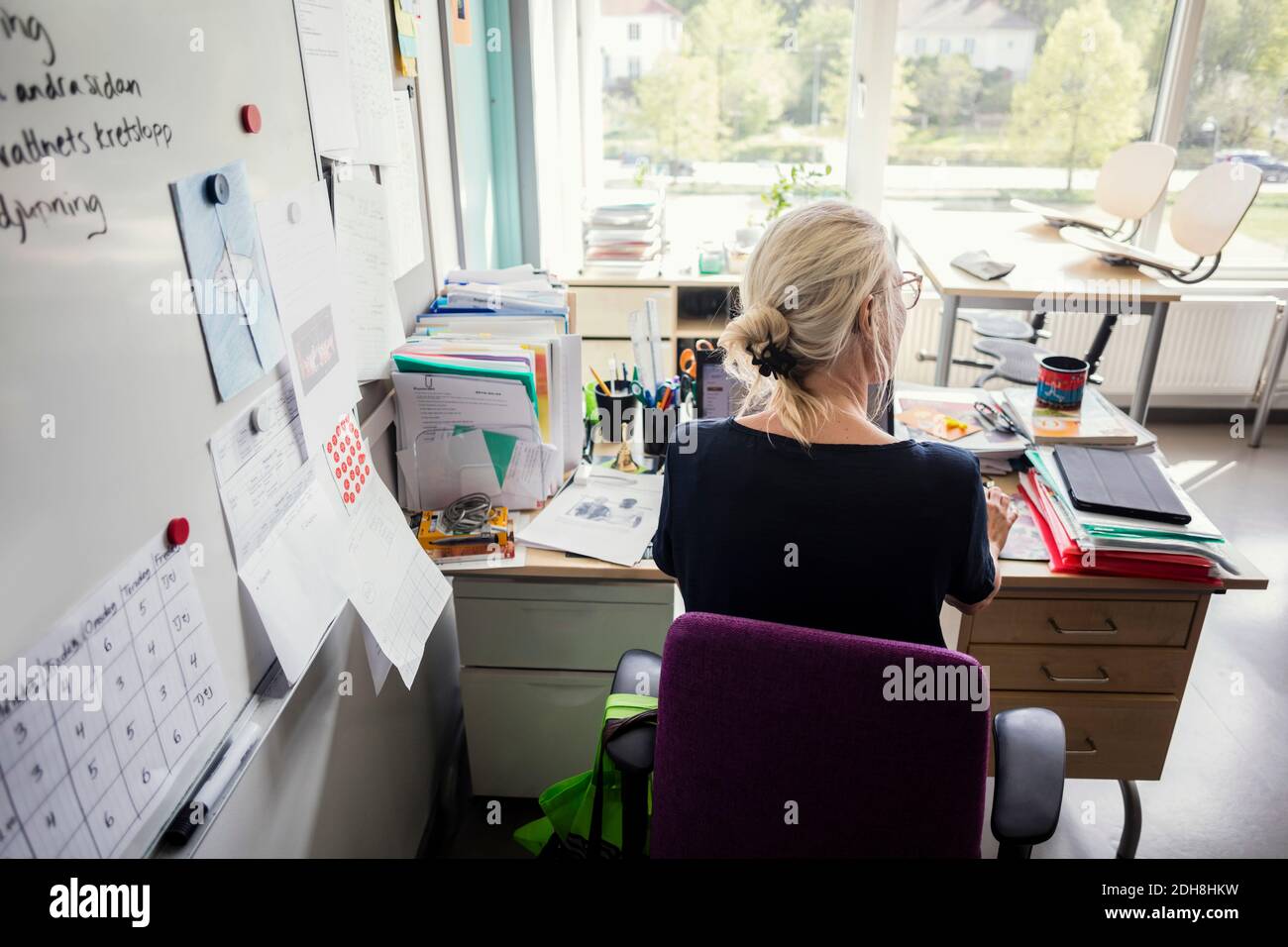 Vue arrière de l'enseignant utilisant un ordinateur portable dans la salle de classe Banque D'Images