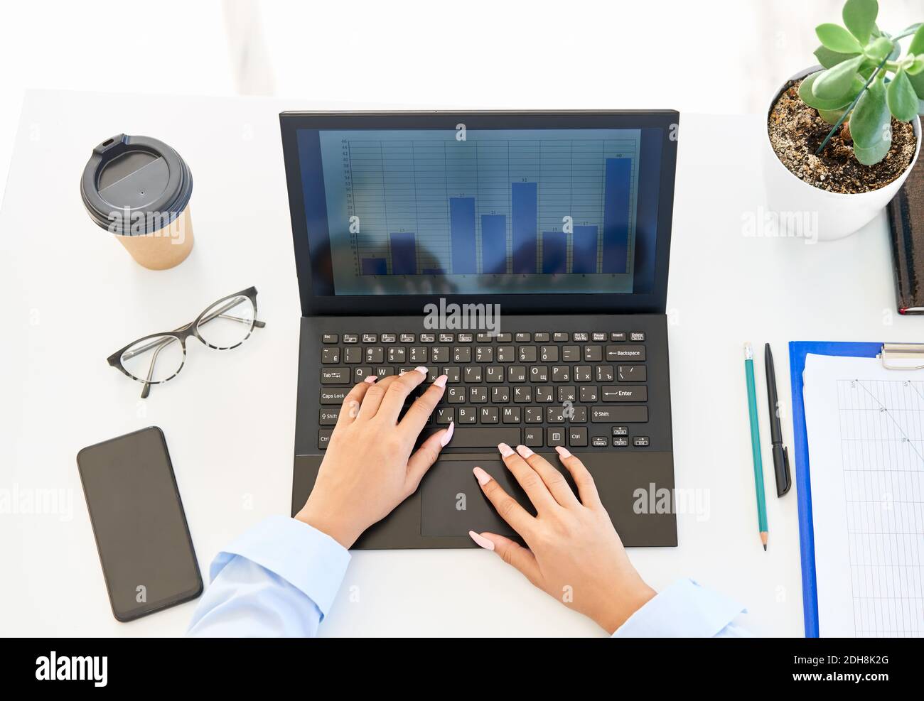 Vue de dessus des mains de femme d'affaires tapant sur un ordinateur portable table de bureau blanche moderne Banque D'Images