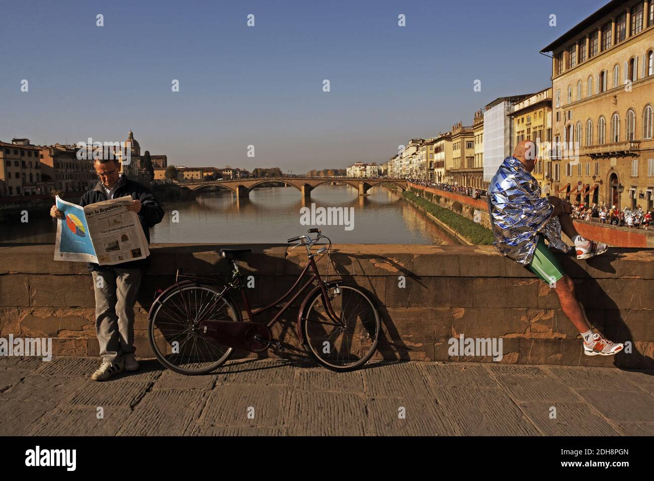 Italie, Toscane, Florence, rivière Arno avec Ponte alla Carraia pendant le marathon de Florence ayant une pause avec une couverture d'argent enveloppée autour . Banque D'Images