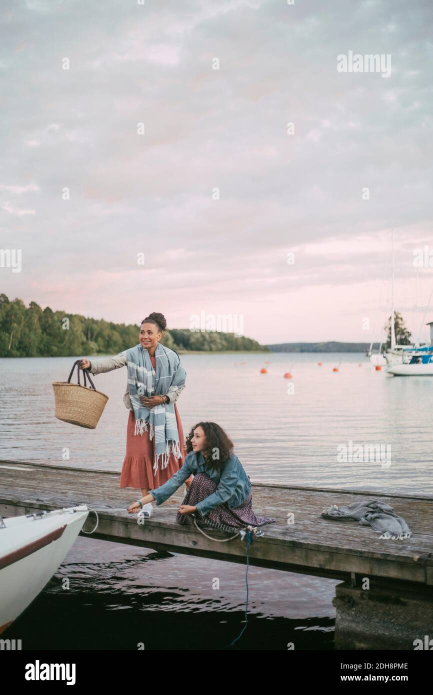 Fille tenant l'ancre par la mère sur la jetée au-dessus du lac pendant coucher de soleil Banque D'Images