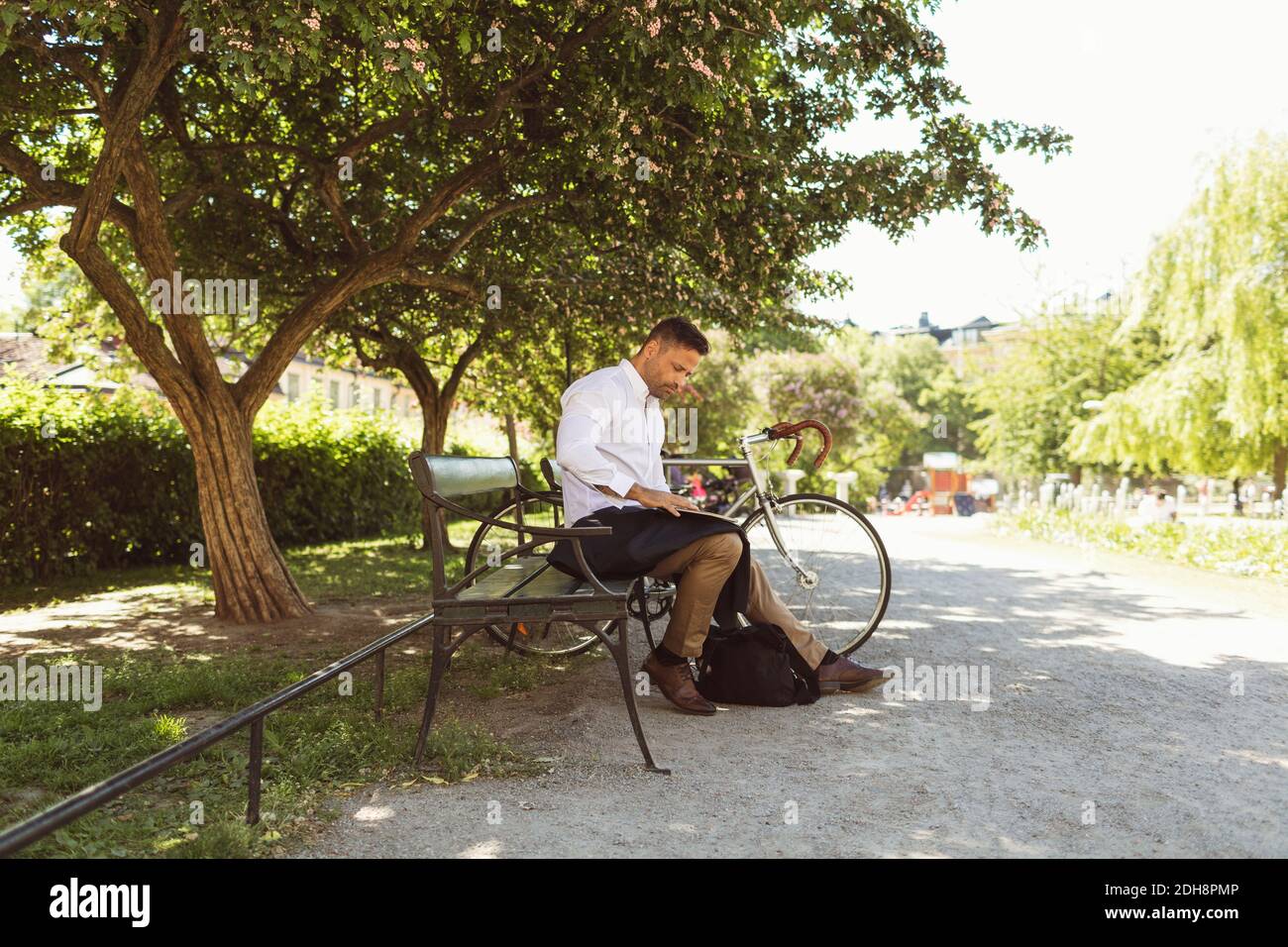 Homme d'affaires utilisant un ordinateur portable assis sur un banc au parc Banque D'Images