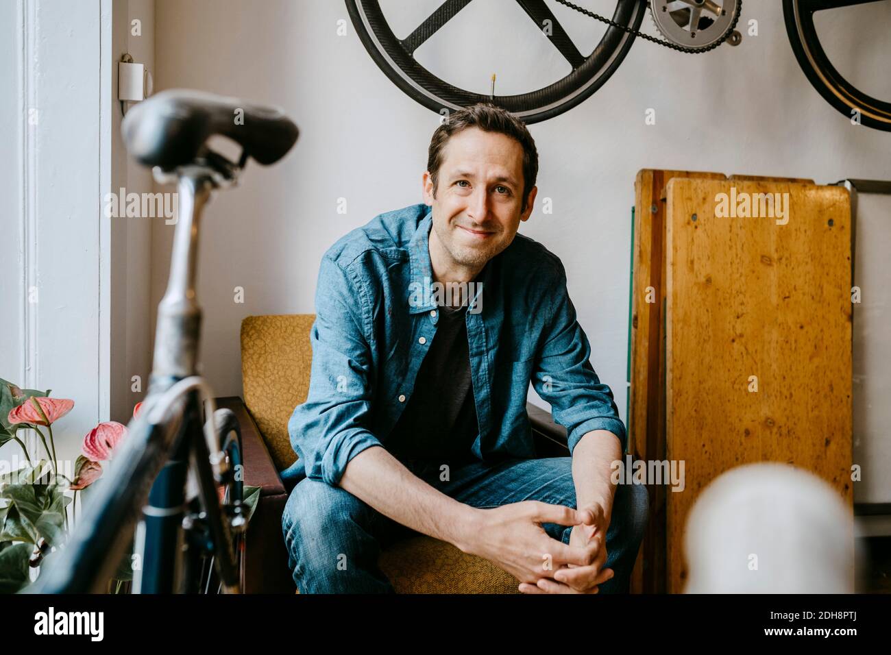 Portrait d'un homme souriant assis dans une boutique de vélos Banque D'Images
