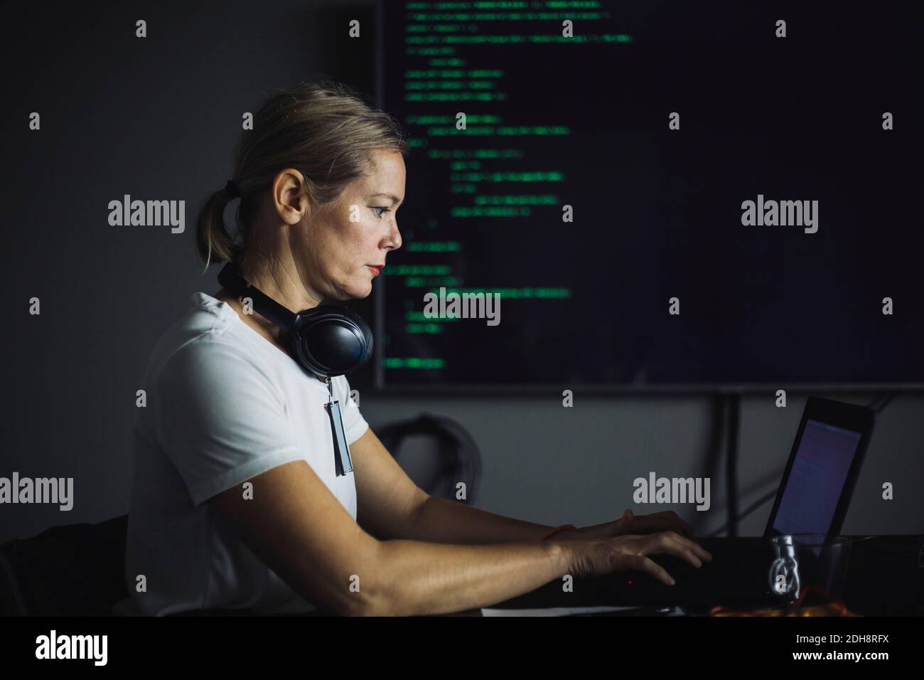 Vue latérale du PROFESSIONNEL DE L'INFORMATIQUE travaillant sur un ordinateur portable au bureau Banque D'Images
