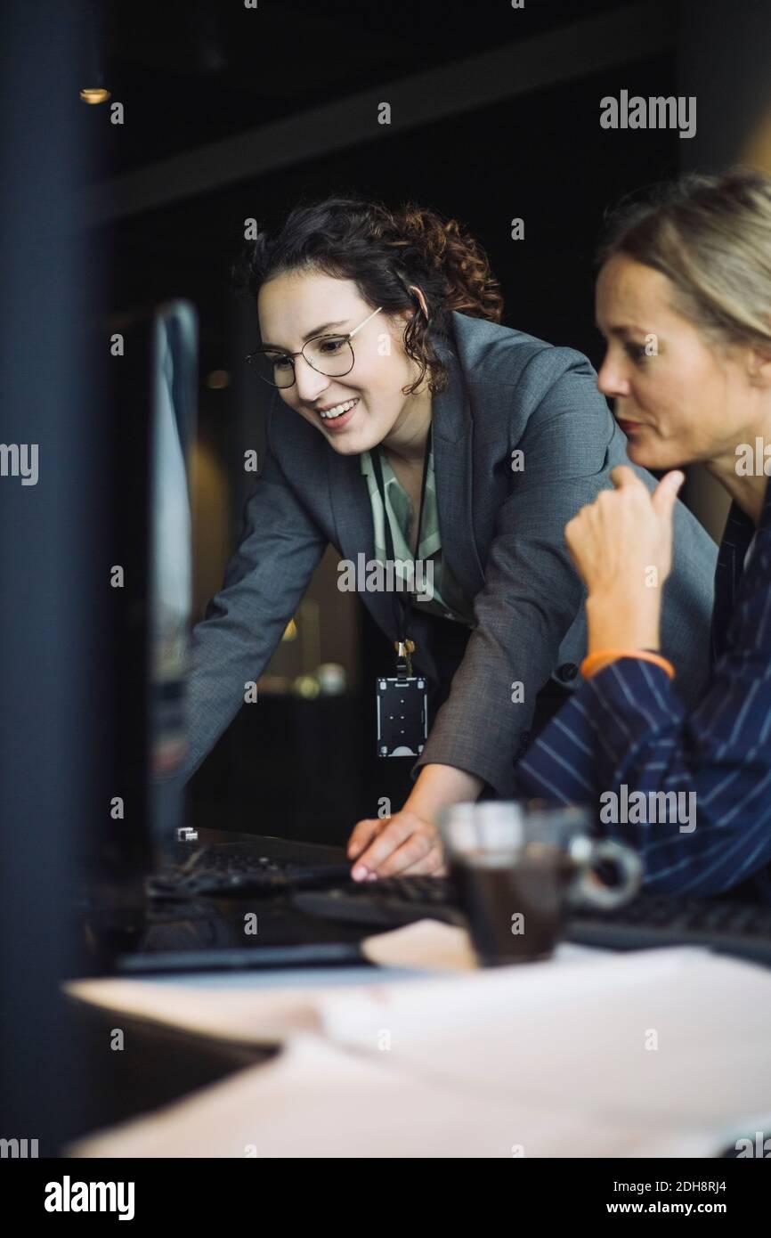 Souriante femme INFORMATICIENS travaillant sur ordinateur au bureau Banque D'Images