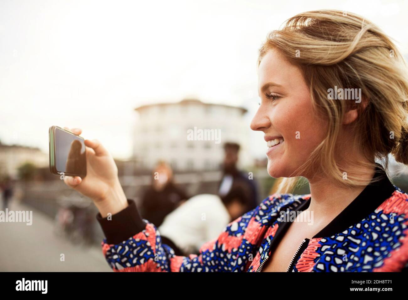 Vue latérale d'une femme heureuse photographiant depuis un smartphone Banque D'Images