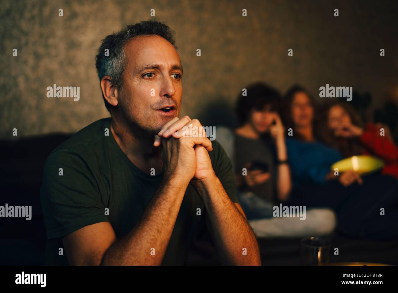 Homme plein d'espoir priant tout en regardant le sport la nuit Banque D'Images