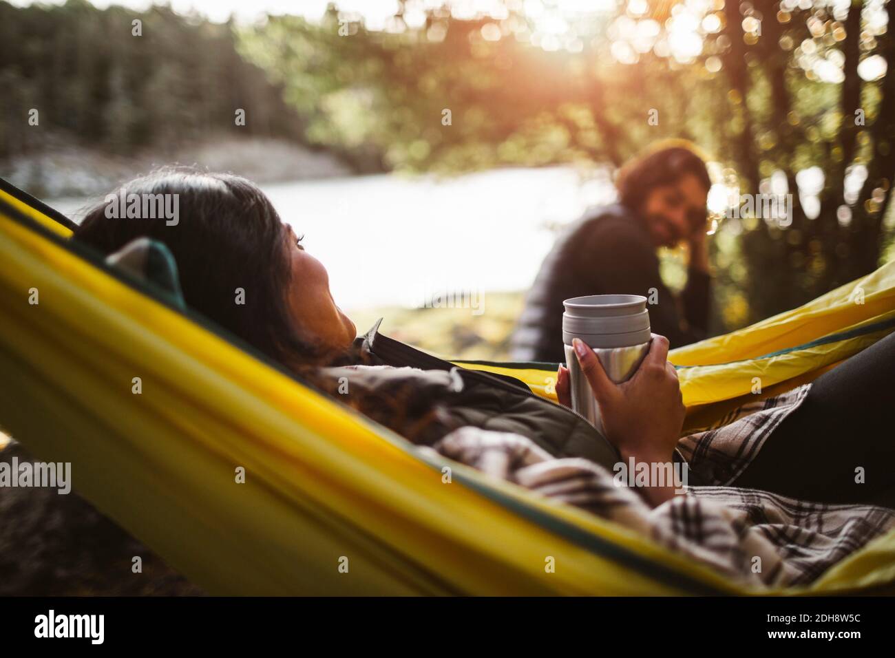 Vue latérale d'une femme avec un ami sur un hamac en forêt Banque D'Images