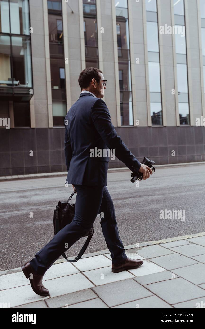 Vue latérale de l'homme d'affaires avec sac marchant sur le trottoir à l'intérieur ville Banque D'Images