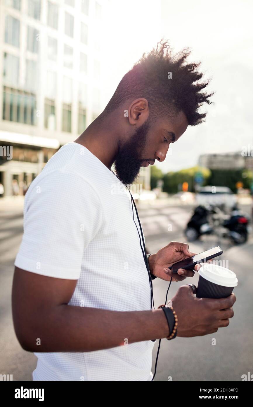 Jeune homme en profil à l'aide d'un smartphone Banque D'Images