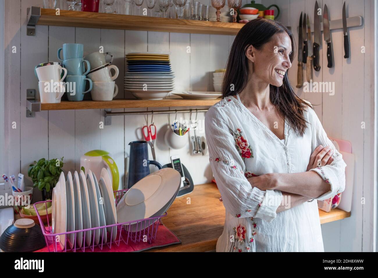 Bonne femme debout au comptoir avec les bras croisés dans la cuisine à la maison Banque D'Images