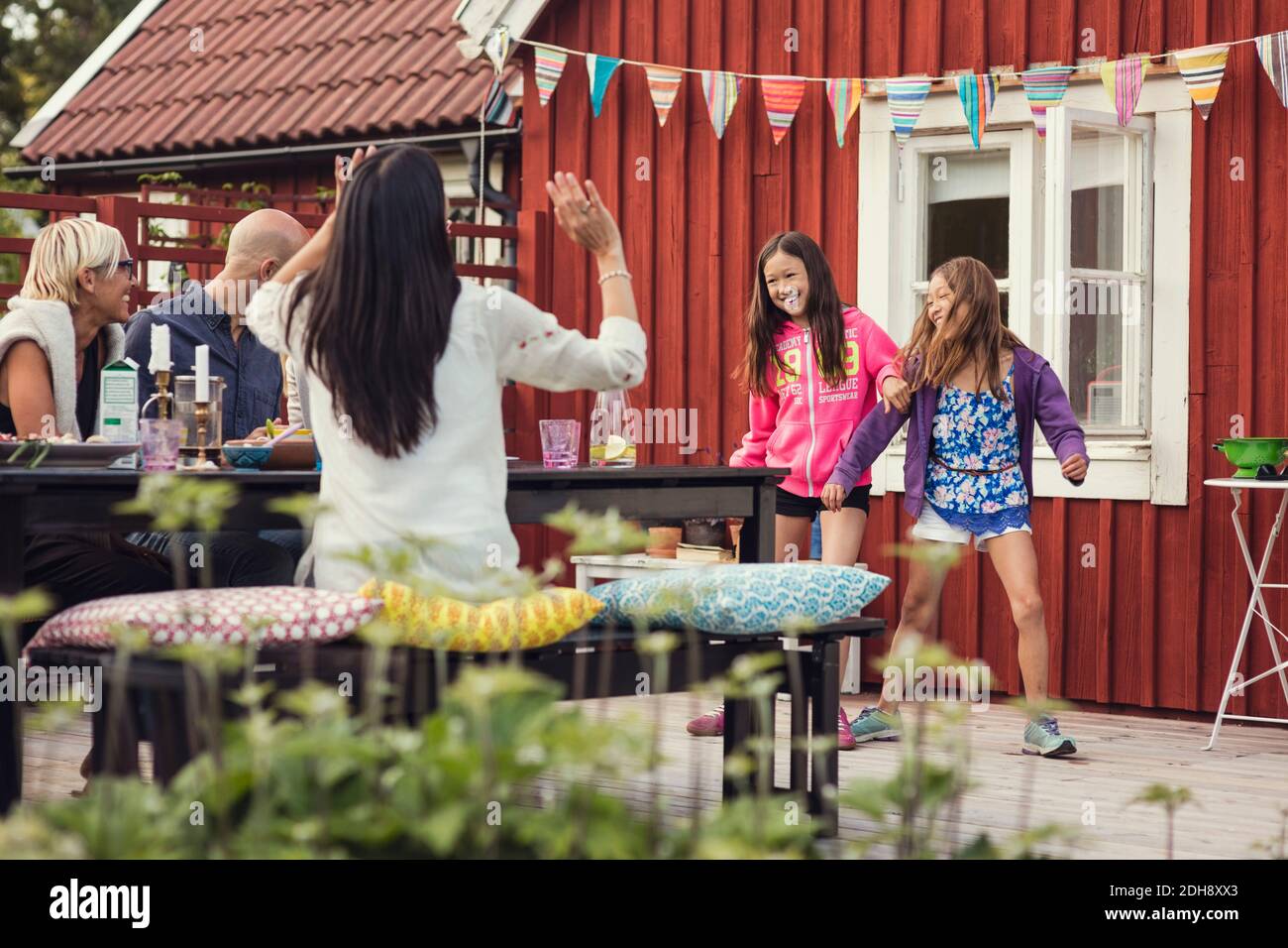 Famille et amis heureux regardant les filles danser dans la cour arrière pendant la fête dans le jardin Banque D'Images