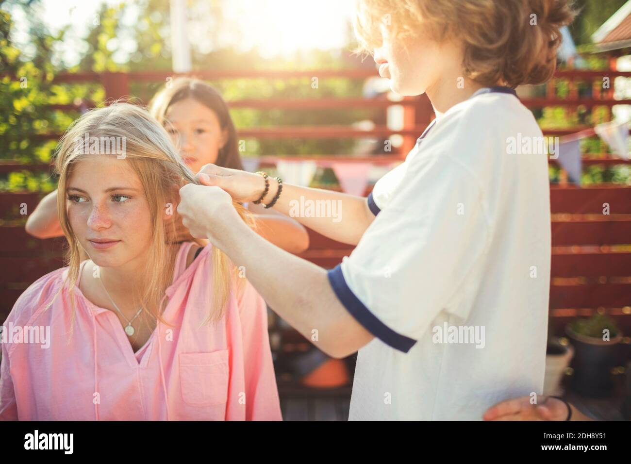 Des amis qui brasure les cheveux d'une adolescente dans la cour arrière Banque D'Images