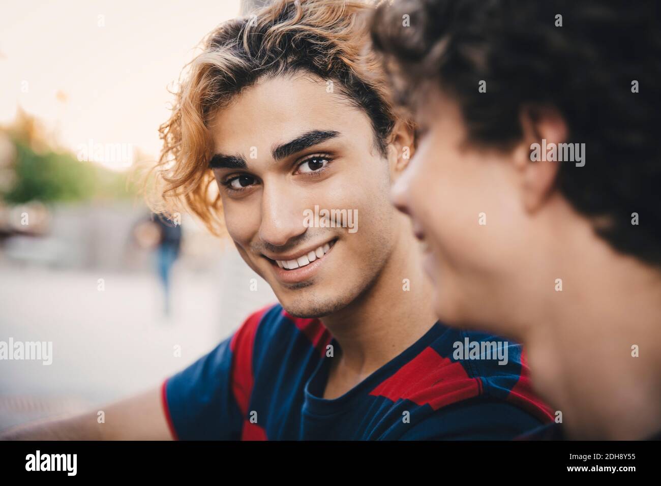 Portrait d'un homme souriant avec un ami assis en ville Banque D'Images