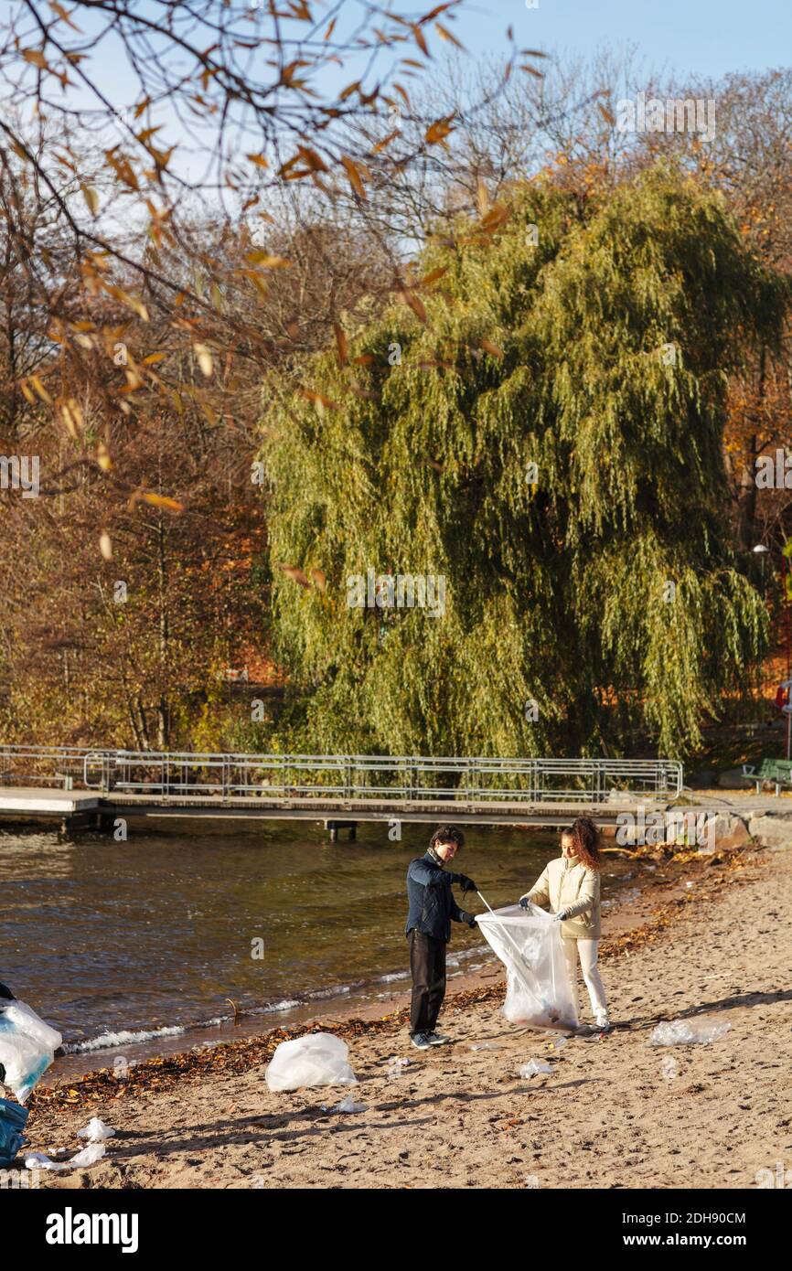 Des amis mâles et femelles ramassant les ordures au bord du lac Banque D'Images