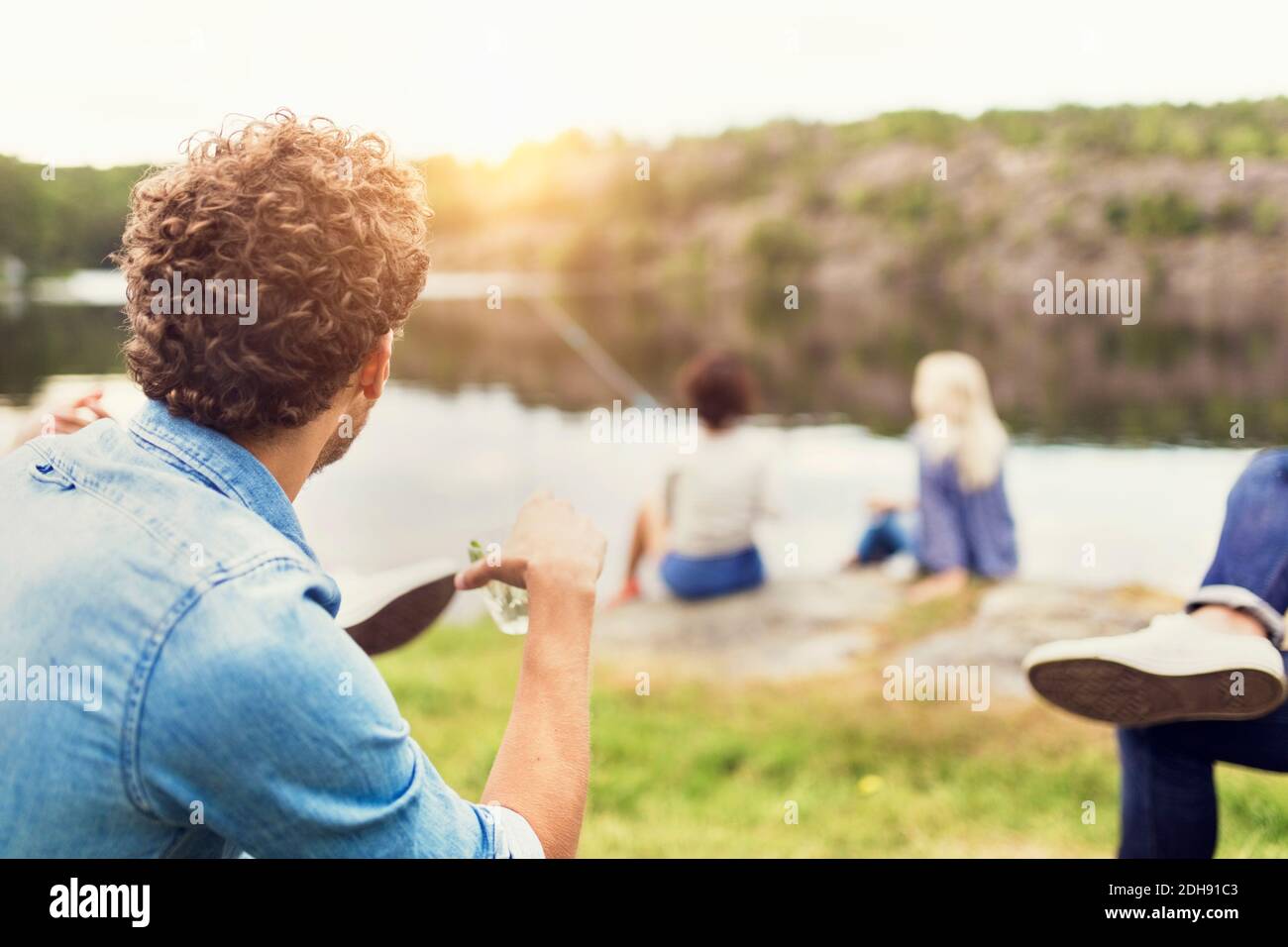 Les hommes qui ont bu pendant que les amis femelles pêchent sur le bord du lac Banque D'Images