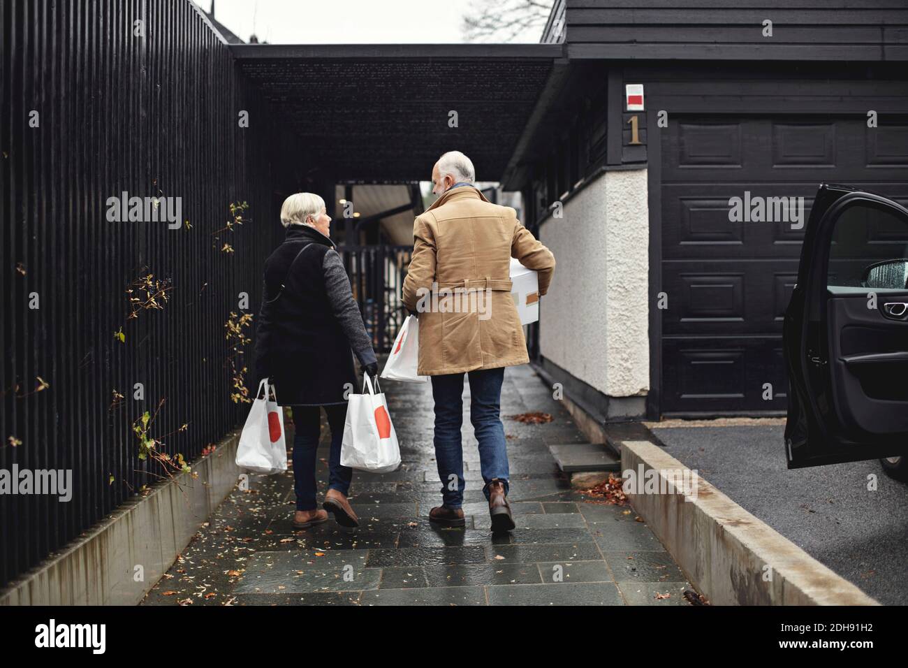 Vue arrière du couple senior avec les sacs qui marchent ensemble trottoir en hiver Banque D'Images