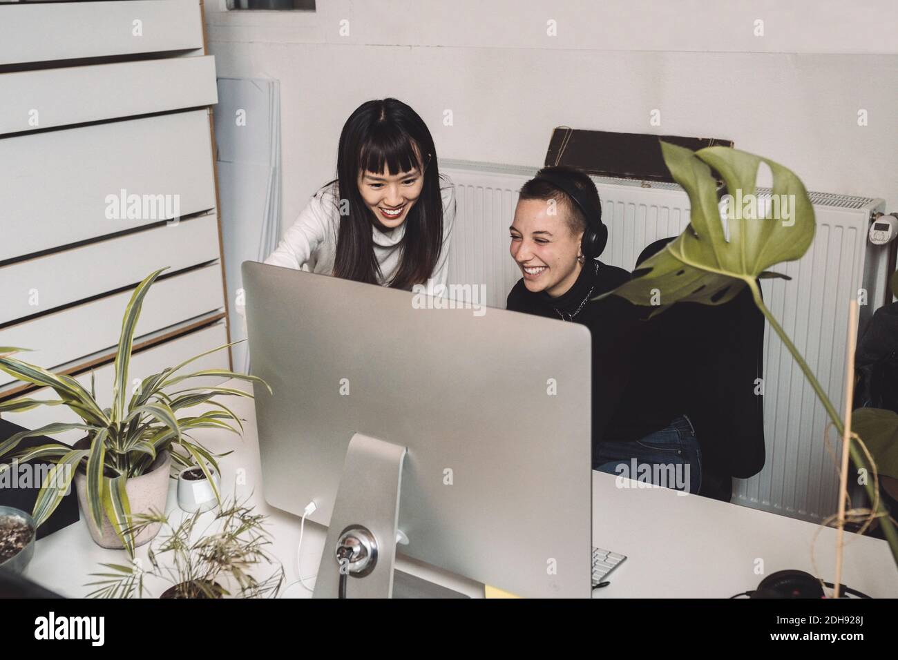 Des entrepreneurs souriants travaillant sur ordinateur sur le lieu de travail Banque D'Images